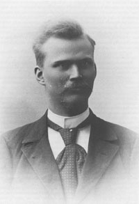 Kuva 7. Albert Tallroth (1871–1899). – Kuurojen Liitto ry, Kuurojen museo. Mustavalkoinen ritakuva viiksekkäästä vaaleahiuksisesta miehestä jolla valkoinen paita, tumma puvuntakki ja ruudullinen kravatti.